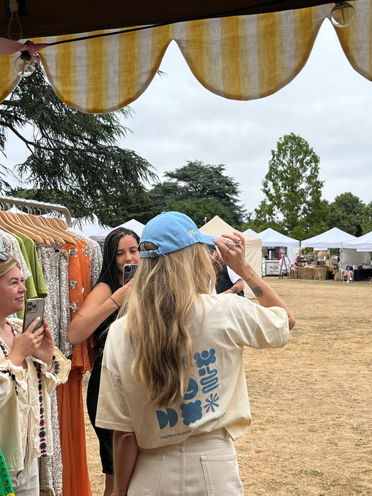 Fearne Cotton wearing her personalised Never Fully Dressed x Happy Place Festival cap, embroidered live by Beth Wilson Embroidery during a live event activation.