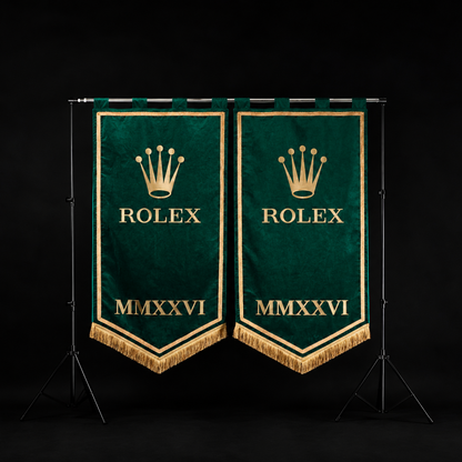 Two matching green Rolex pennant banners with gold embroidery, displayed side-by-side on a black studio background stand.
