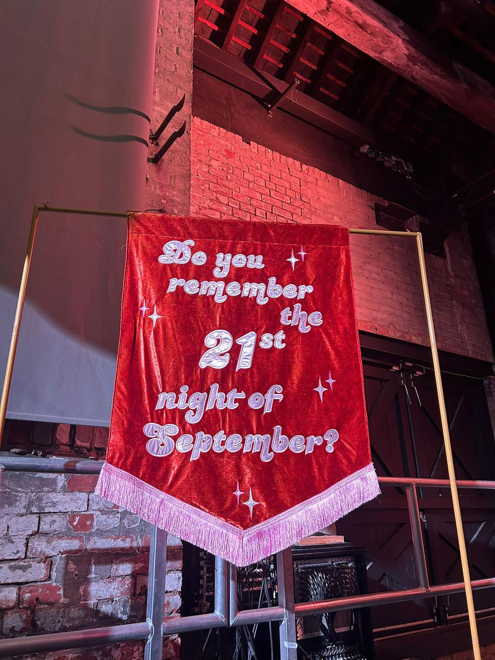 A super size large velvet banner hanging on a pole at a wedding, stitched with "do you remember the 21st of september" in satin and luxury embroidery. With a tassel. 