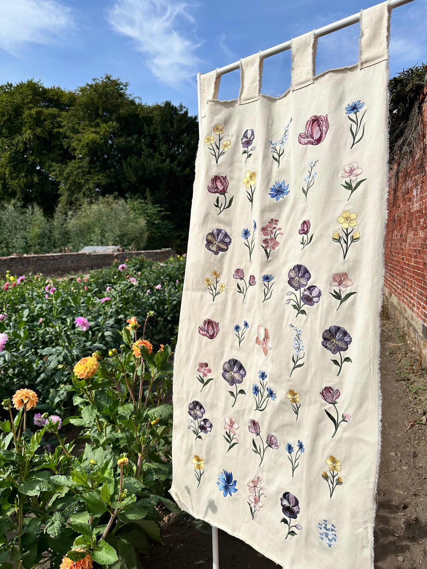 Flowers embroidered on to neutral banner, blowing in the wind in a flower field 