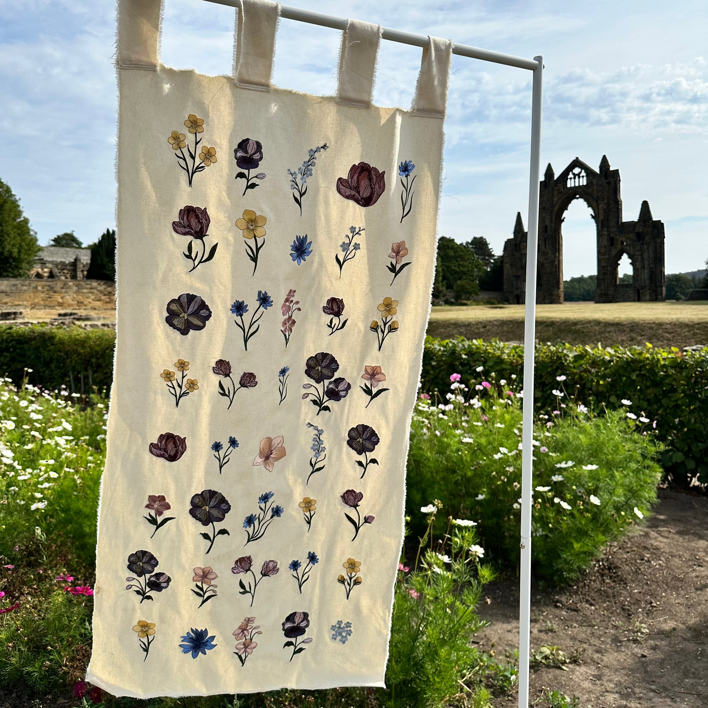 Beautiful florals embroidered onto a canvas banner hanging in Priory Rowes Flower Garden