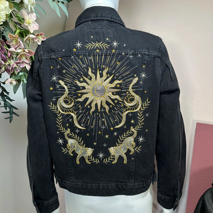 Black denim jacket with celestial design on a mannequin against a neutral background