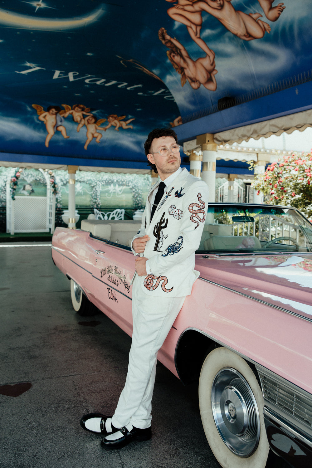 Groom in a white suit. The blazer is embroidered with vintage vegas old money casino style imagery. 