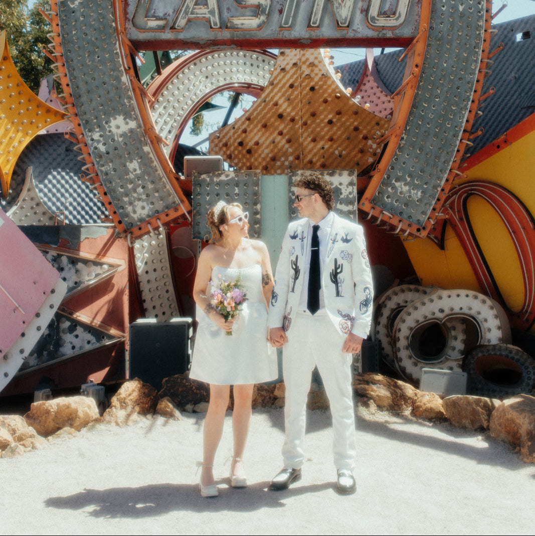 Bespoke embroidered white wedding blazer for a Las Vegas wedding, featuring custom western-inspired and Vegas-themed embroidery details. Luxury made-to-order groom jacket designed for an alternative modern wedding look.