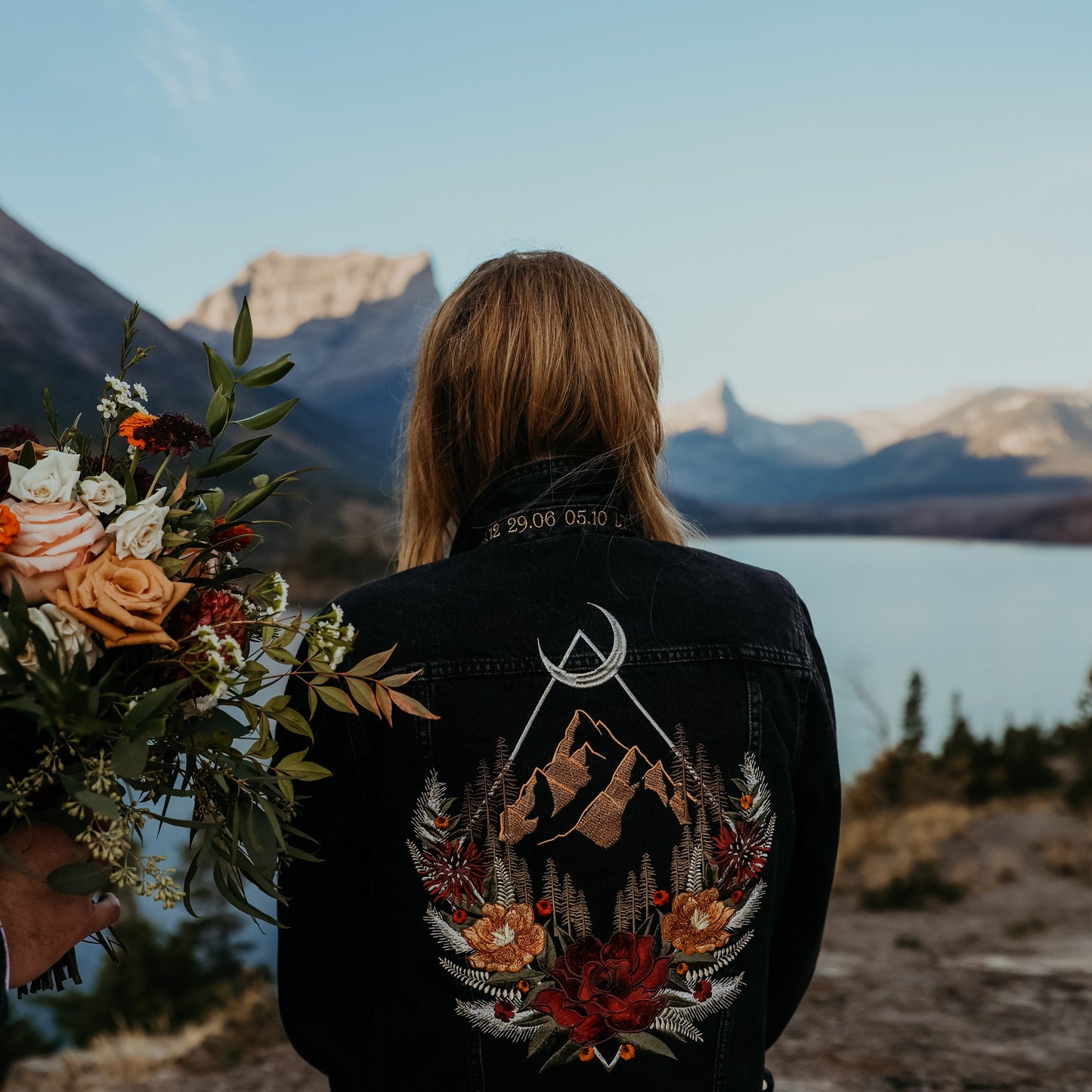 bride wearing a personalised embroidered floral denim jacket during a mountain elopement wedding.