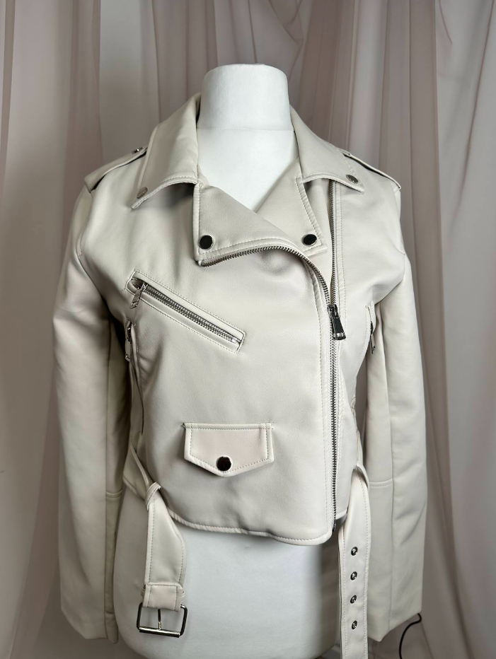 A cropped faux leather moto jacket in off-white/cream, displayed on a white mannequin torso against a draped beige curtain background.
