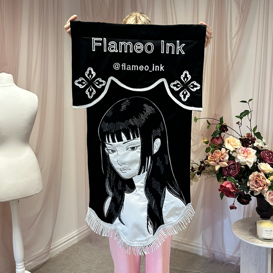 Custom velvet banner with white fringe for tattoo studio, double-layer design showcasing independent shop branding and logo.
A premium double-layer velvet banner with soft white fringe, designed for a tattoo studio, showcasing custom branding in a bold and luxurious style. Ideal for independent tattoo shops looking for high-impact wall decor that reflects their identity and artistic style.