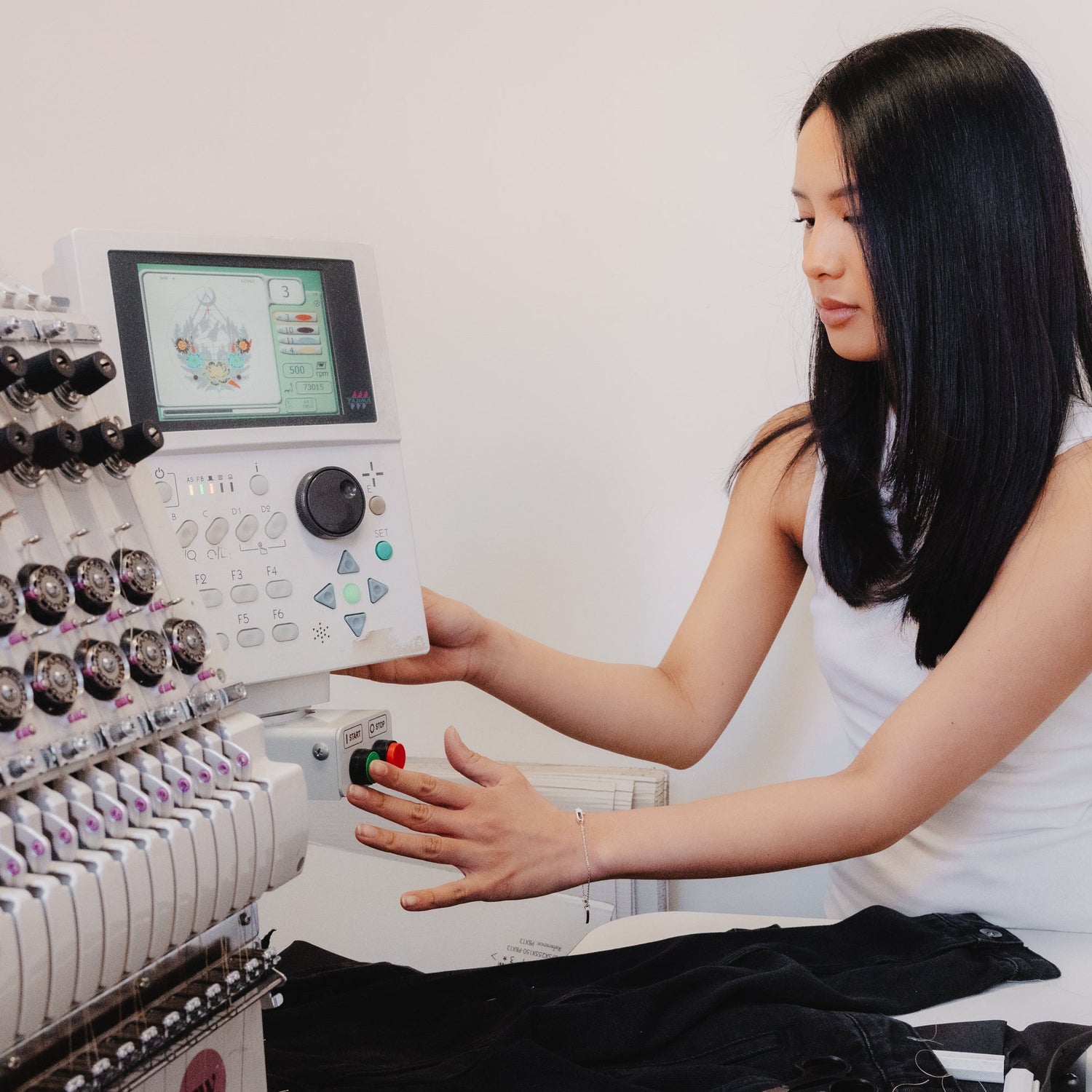 Woman operating an embroidery machine with a white background