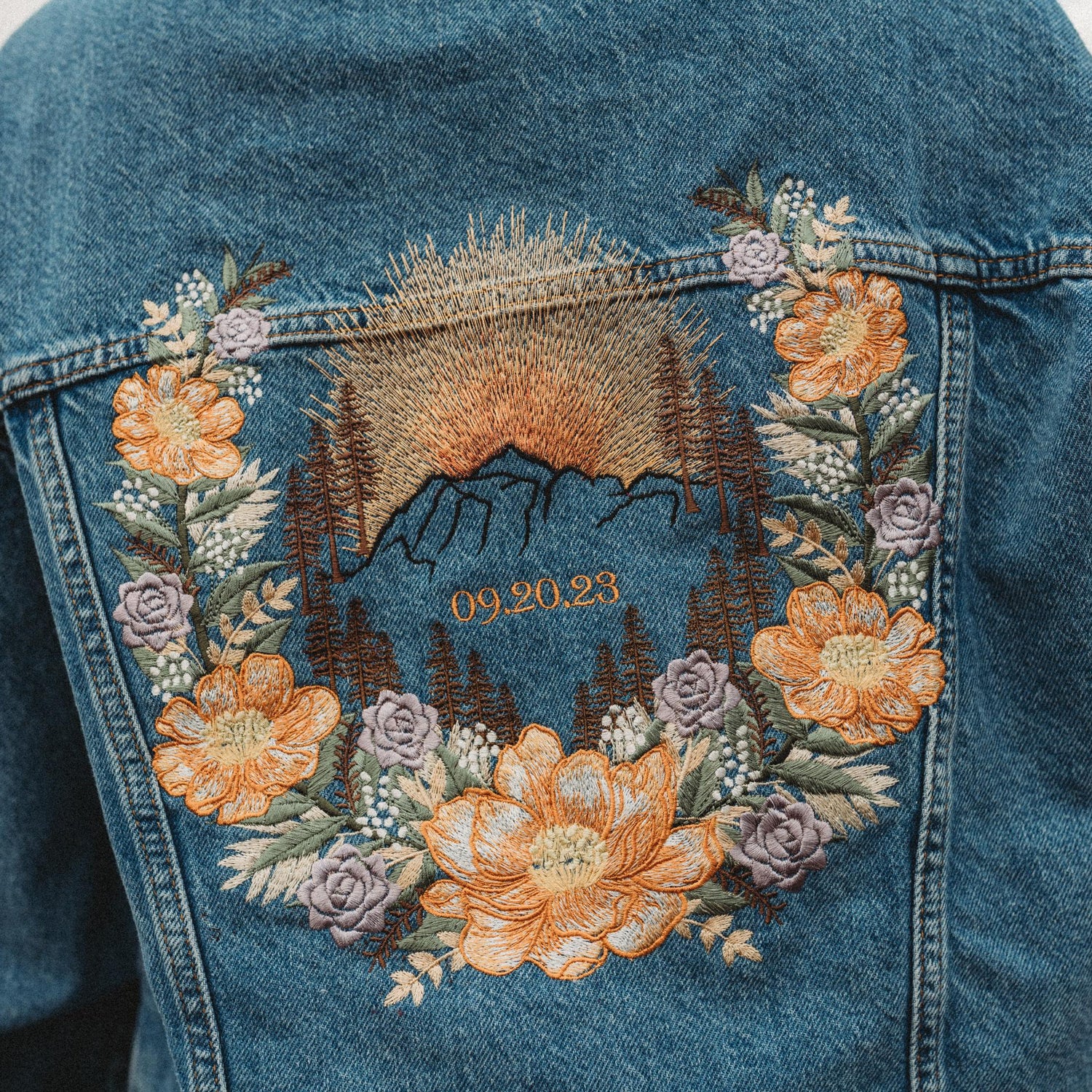 Denim jacket with embroidered mountain and floral design for elopement bride