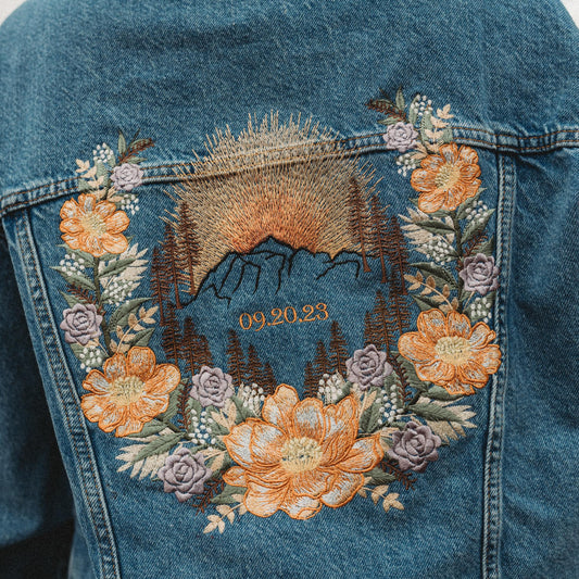 Denim jacket with embroidered mountain and floral design for elopement bride