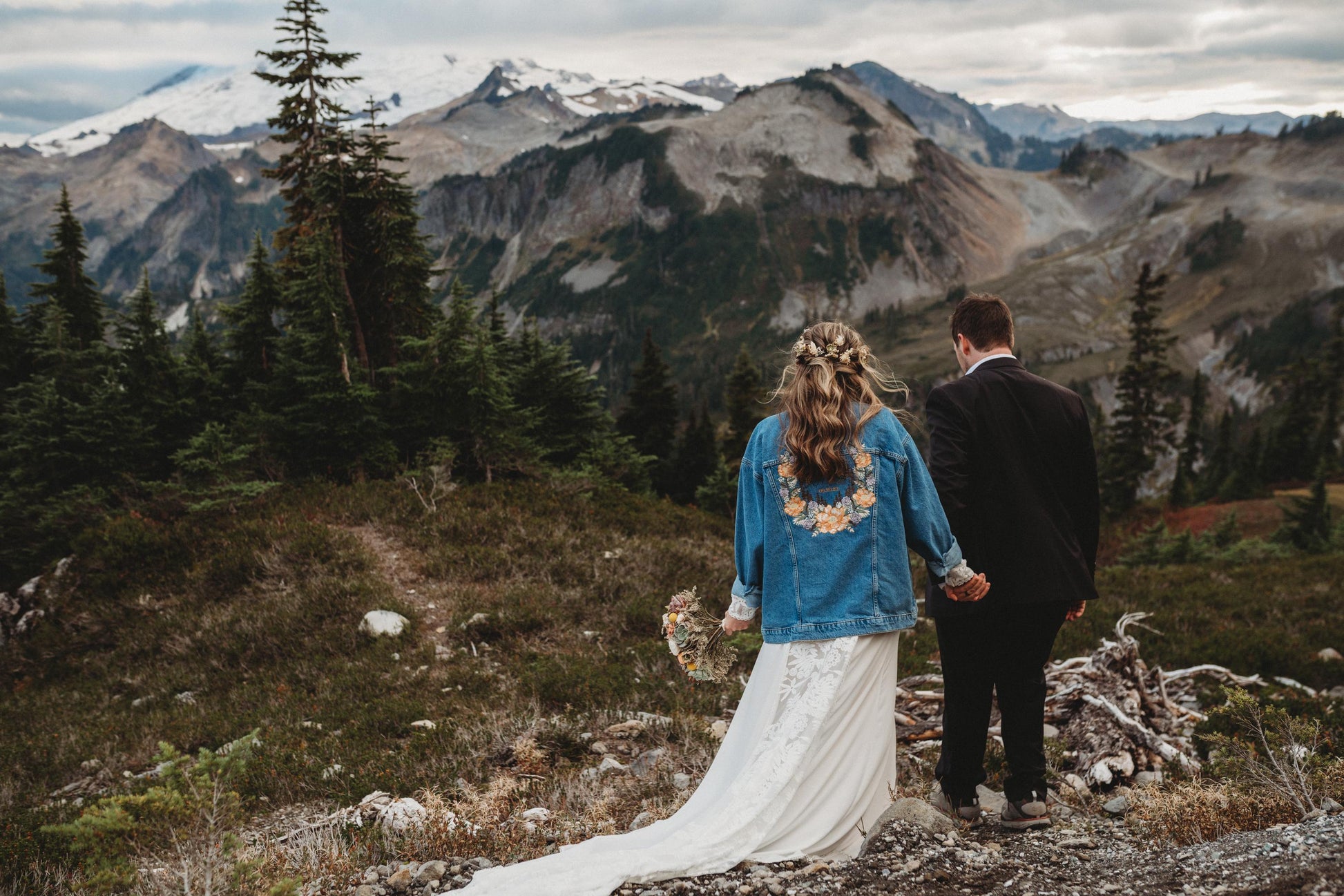 Couple standing on a mountain with a scenic view of mountains and trees.