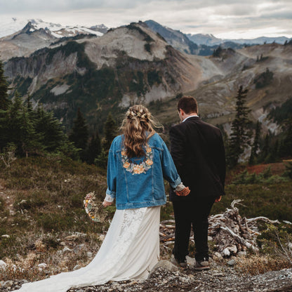 Couple standing on a mountain with a scenic view of mountains and trees.